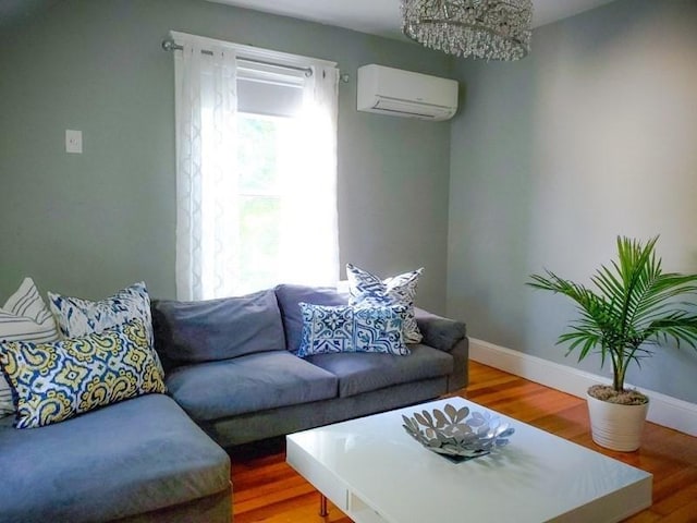 living room with a wall mounted air conditioner, hardwood / wood-style flooring, and an inviting chandelier