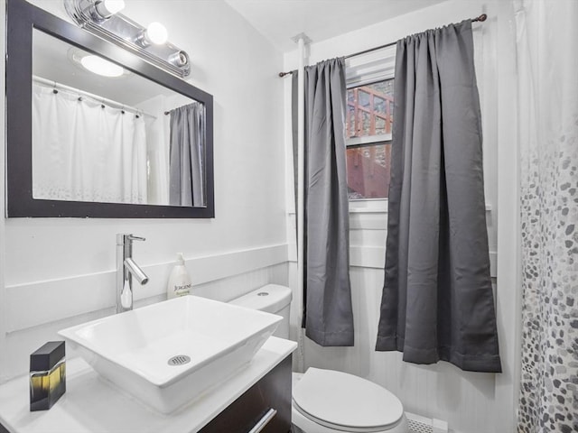 bathroom featuring vanity, toilet, and walk in shower