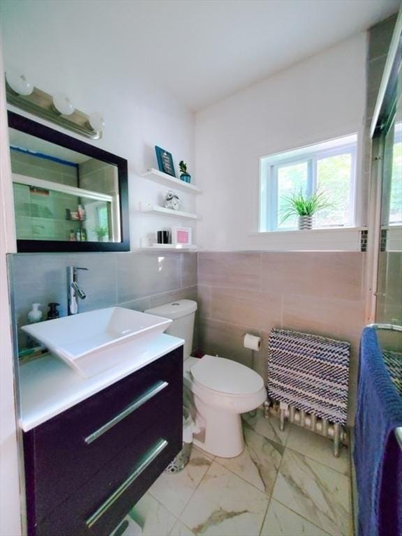 bathroom with walk in shower, vanity, toilet, and tile walls