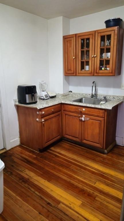 bar with light stone countertops, dark hardwood / wood-style flooring, and sink