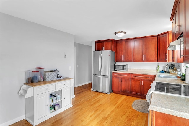 kitchen featuring sink, light wood-type flooring, extractor fan, and appliances with stainless steel finishes