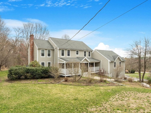 view of front facade featuring a front yard, a shingled roof, a chimney, and covered porch