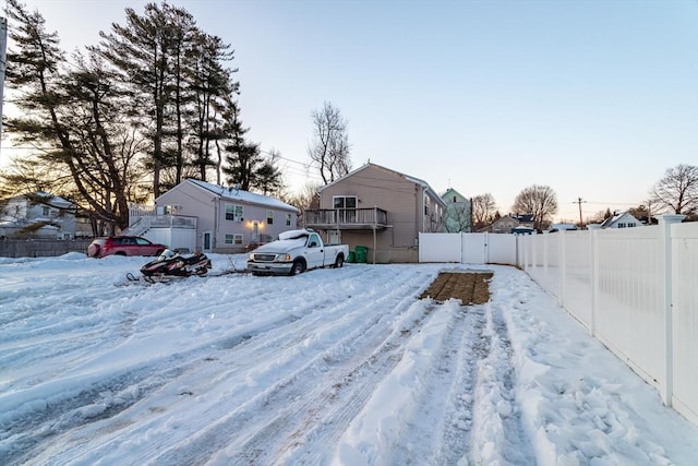 snowy yard with a residential view and fence