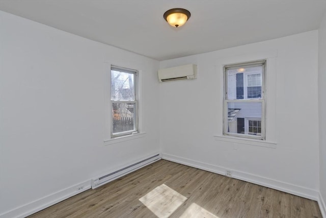 unfurnished room featuring a baseboard heating unit, baseboards, wood finished floors, and a wall unit AC