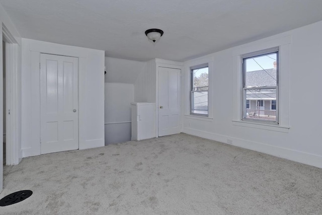 unfurnished bedroom with carpet, multiple closets, and baseboards