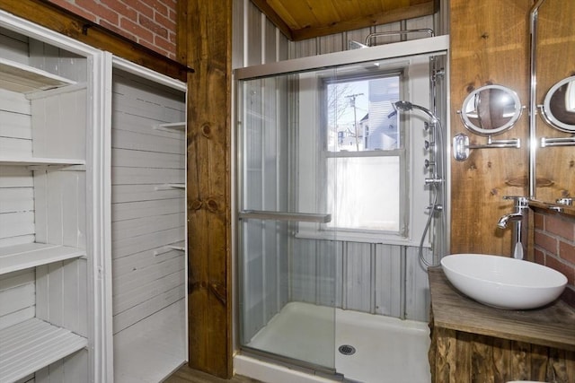 bathroom with wooden walls, a stall shower, and vanity