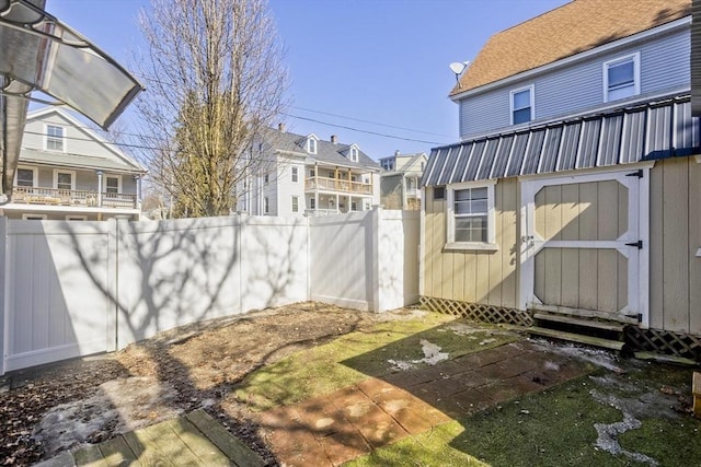 view of yard with a fenced backyard, a residential view, a storage shed, and an outdoor structure