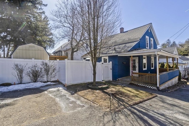 view of front of property featuring a porch, a shingled roof, and fence