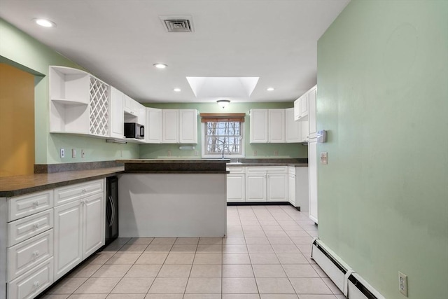 kitchen with a skylight, sink, white cabinets, washer / clothes dryer, and light tile patterned flooring