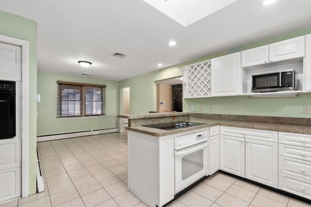 kitchen with light tile patterned floors, baseboard heating, kitchen peninsula, white cabinets, and black appliances