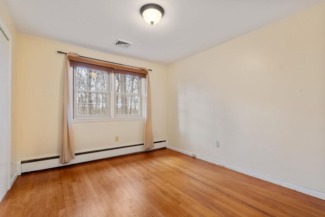 empty room featuring light wood-type flooring and a baseboard heating unit