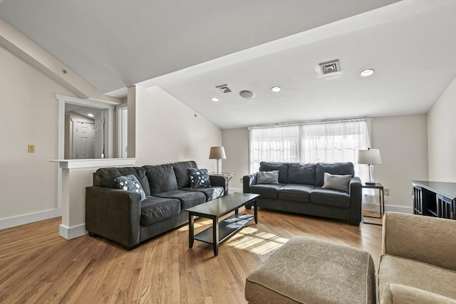 living area featuring lofted ceiling, light wood-type flooring, visible vents, and baseboards