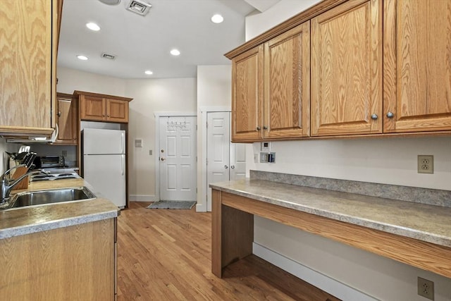 kitchen with light wood-style flooring, recessed lighting, a sink, visible vents, and freestanding refrigerator