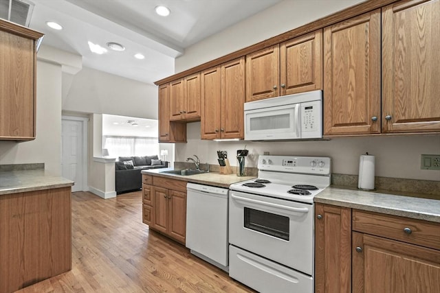 kitchen featuring white appliances, brown cabinets, and a sink