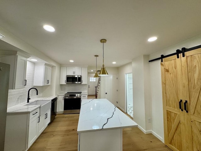 5 Mechanic St, Brookfield, MA 01506 - kitchen with appliances with stainless steel finishes, a sink, a kitchen island, light wood-style floors, and a barn door