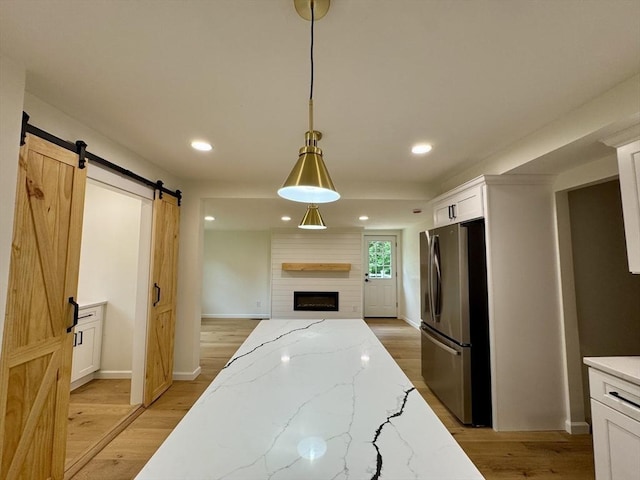 5 Mechanic St, Brookfield, MA 01506 - kitchen featuring freestanding refrigerator, a barn door, white cabinetry, hanging light fixtures, and light wood-type flooring