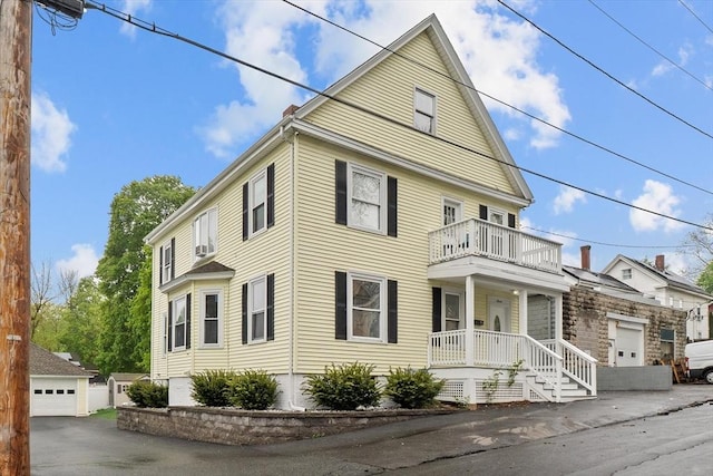 view of front of home featuring covered porch, a balcony, and a detached garage