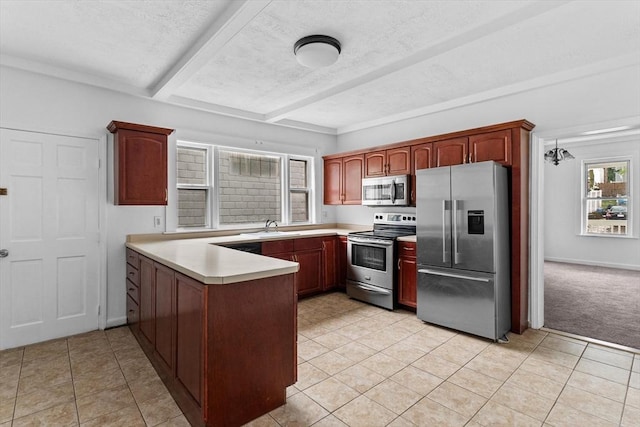 kitchen featuring appliances with stainless steel finishes, a peninsula, a sink, beamed ceiling, and light countertops