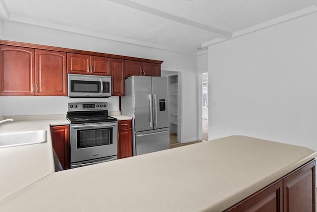 kitchen with appliances with stainless steel finishes, a sink, and light countertops