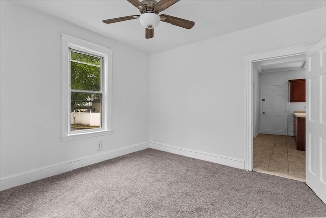 empty room with carpet flooring, ceiling fan, and baseboards
