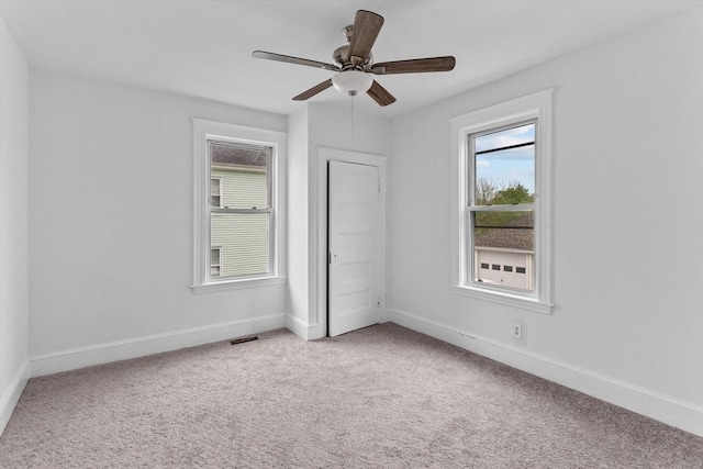 empty room featuring light carpet, baseboards, and a ceiling fan
