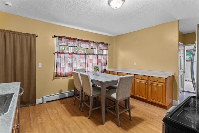 dining space with baseboard heating, light wood-style floors, a textured ceiling, and baseboards