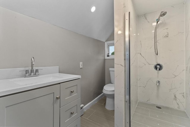 full bath featuring toilet, vanity, a marble finish shower, lofted ceiling, and baseboards