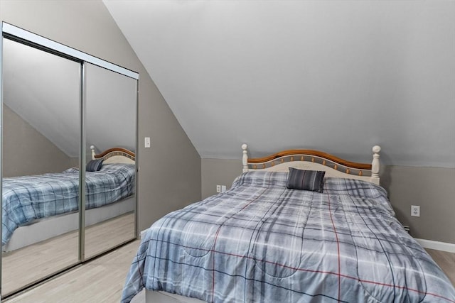 bedroom featuring vaulted ceiling, wood finished floors, a closet, and baseboards