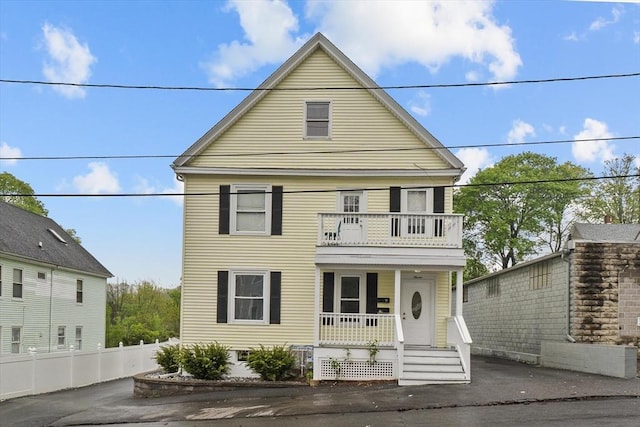 view of front of property with a balcony, a porch, and fence