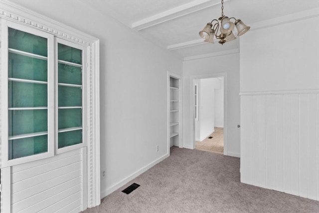 spare room with a chandelier, carpet, and beam ceiling