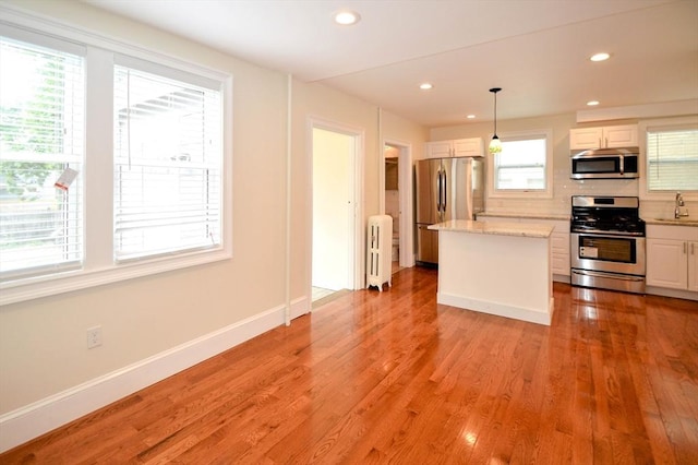 kitchen featuring white cabinets, radiator, light wood-style flooring, and stainless steel appliances