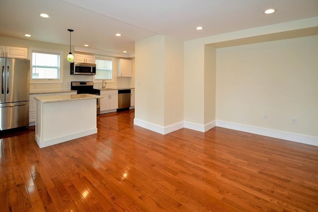 kitchen featuring backsplash, dark wood-style floors, white cabinetry, stainless steel appliances, and baseboards