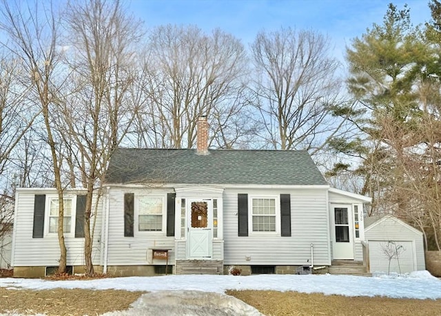 view of front of property featuring an outbuilding, a detached garage, a chimney, a shingled roof, and entry steps