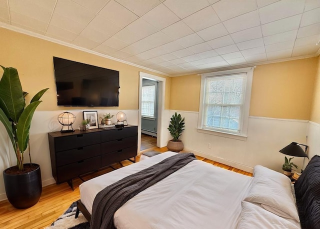 bedroom with baseboards, crown molding, a baseboard heating unit, and wood finished floors