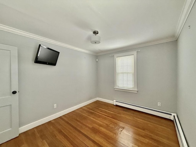 spare room featuring baseboards, a baseboard radiator, wood finished floors, and crown molding