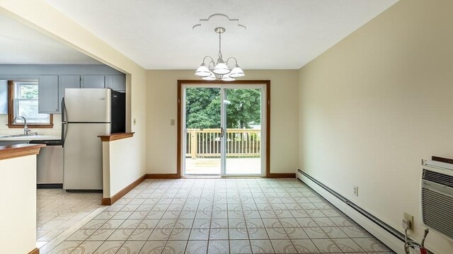 kitchen featuring sink, appliances with stainless steel finishes, a baseboard heating unit, hanging light fixtures, and a chandelier