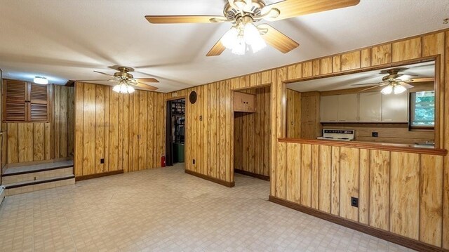 unfurnished living room featuring wooden walls and ceiling fan