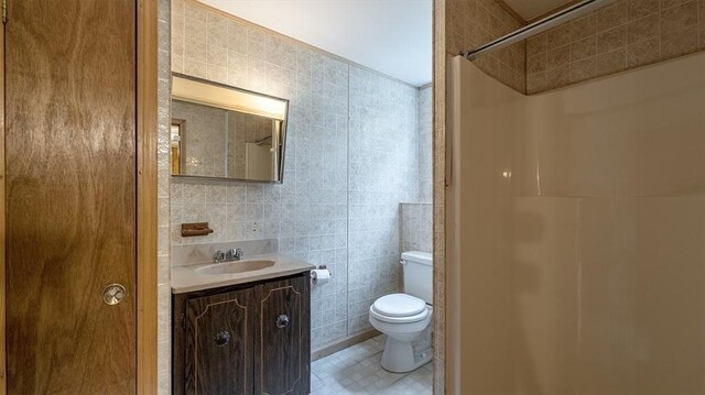 bathroom featuring tile walls, vanity, a shower, and toilet