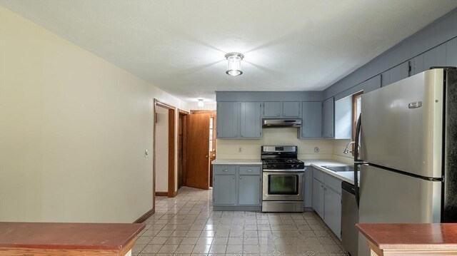 kitchen with appliances with stainless steel finishes, sink, and gray cabinetry