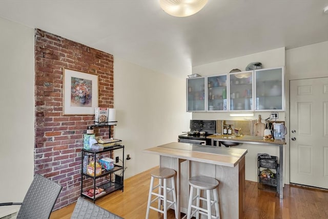 bar featuring black electric range, white cabinetry, and light hardwood / wood-style flooring