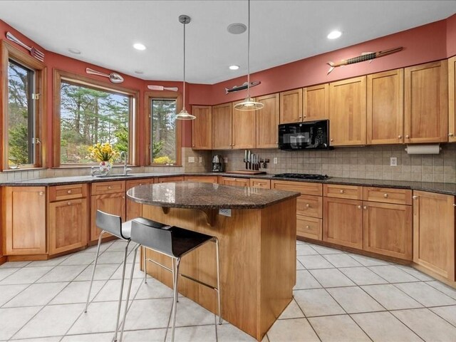 kitchen featuring tasteful backsplash, a sink, black appliances, and a center island