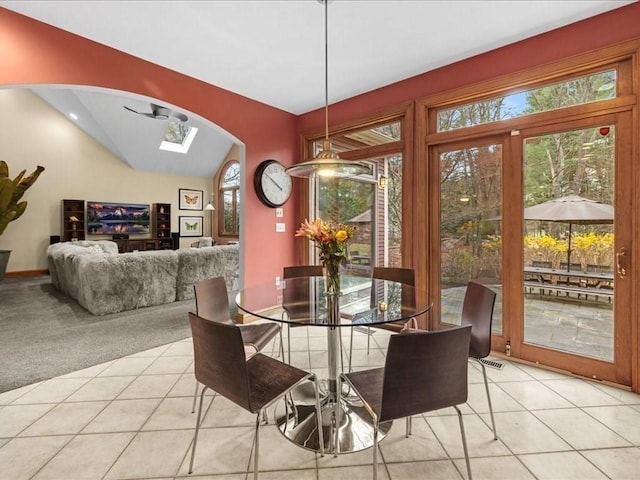 dining area with plenty of natural light, arched walkways, vaulted ceiling, and light carpet