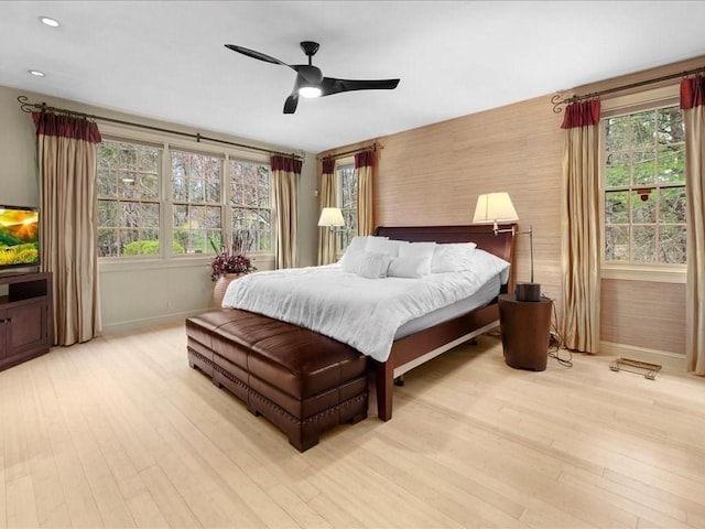 bedroom featuring baseboards, ceiling fan, wood finished floors, and multiple windows