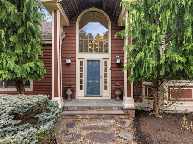 view of exterior entry with a porch and roof with shingles