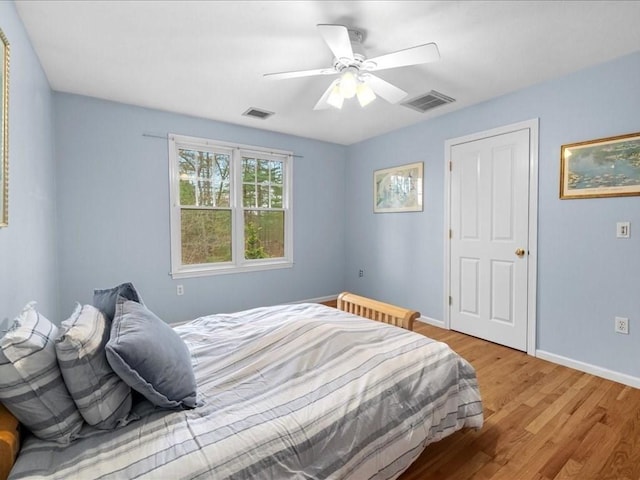 bedroom with baseboards, ceiling fan, light wood finished floors, and visible vents