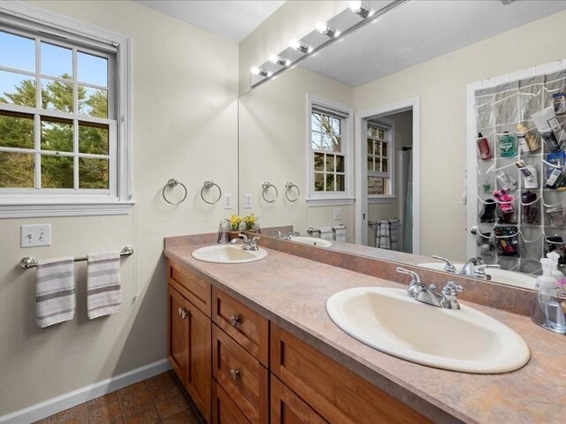 bathroom with a sink, baseboards, and double vanity