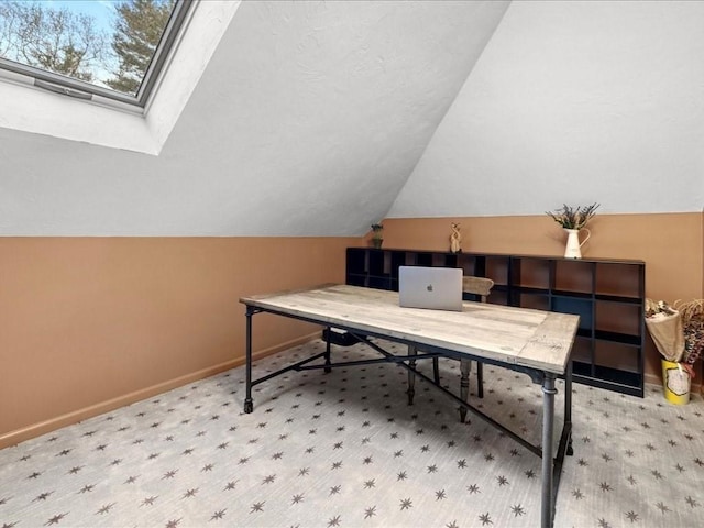 carpeted home office with baseboards and lofted ceiling with skylight