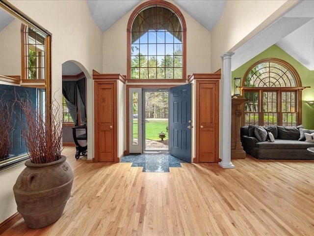 foyer entrance with high vaulted ceiling, ornate columns, wood finished floors, and a wealth of natural light