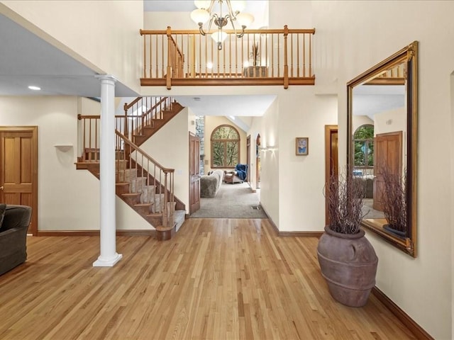 foyer with a chandelier, stairs, baseboards, wood finished floors, and a towering ceiling