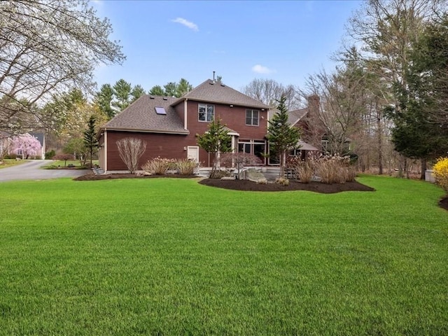 rear view of house featuring a lawn and a shingled roof